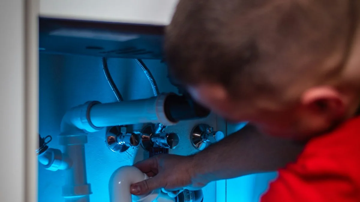 Plumber repairing the trap pipes under a bathroom sink, call tracking for plumbers