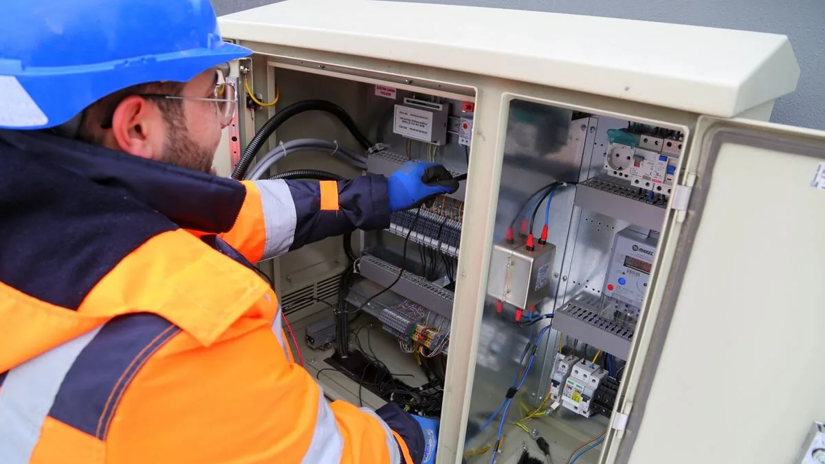 Electrician in hi-vis jacket and helmet working at a fuse box, Local Services Ads vs Search Ads